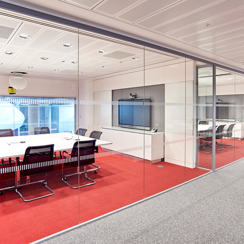 a corporate office interior design with red carpet and glass partitions
